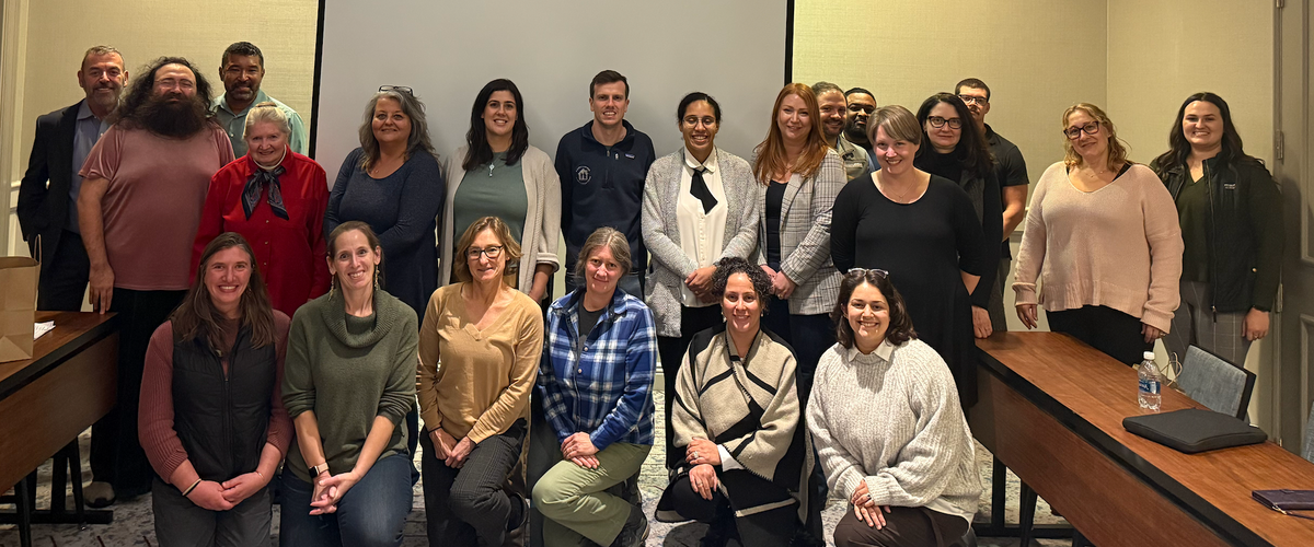 Group photo with RHLI staff and 2025 cohort, standing in front of a screen.